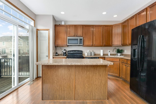 kitchen featuring a sink, a kitchen island, black appliances, and hardwood / wood-style flooring