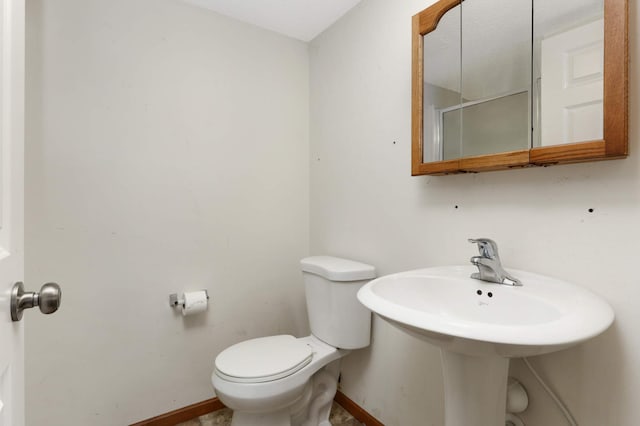 bathroom with toilet, baseboards, and a sink