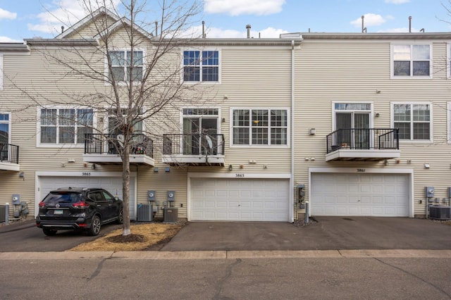 exterior space featuring central AC, an attached garage, and driveway