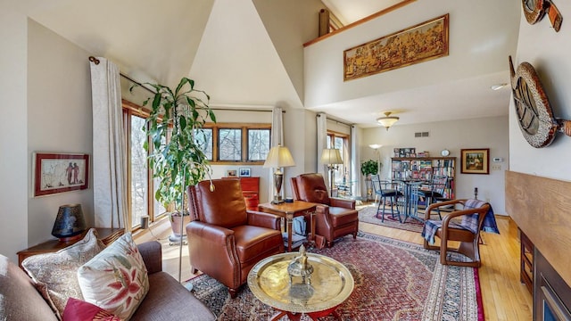 living room featuring plenty of natural light, visible vents, high vaulted ceiling, and wood-type flooring
