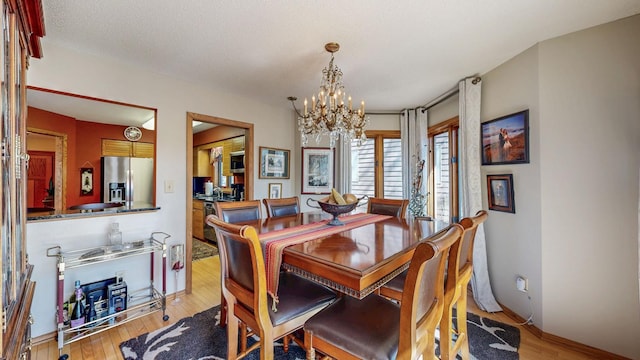 dining area with baseboards, wood finished floors, and a notable chandelier