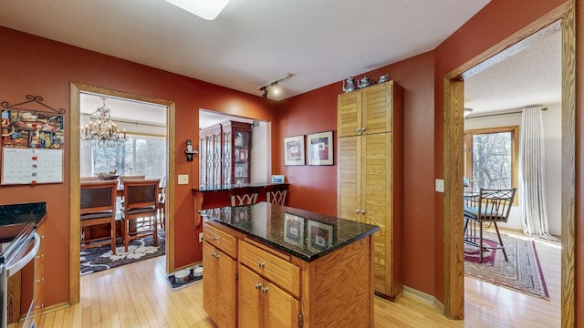 kitchen featuring a wealth of natural light, a chandelier, a kitchen island, and light wood-type flooring