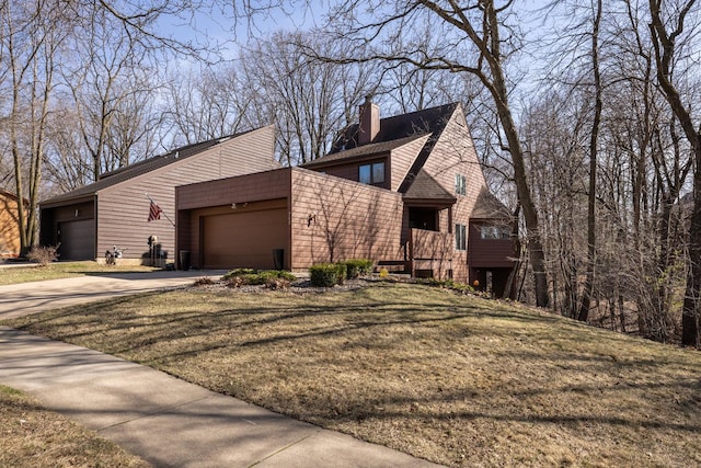view of front of house with a chimney, a front lawn, concrete driveway, an attached garage, and roof with shingles
