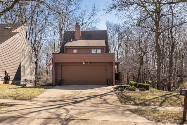 chalet / cabin featuring a shingled roof, a chimney, a front yard, and concrete driveway