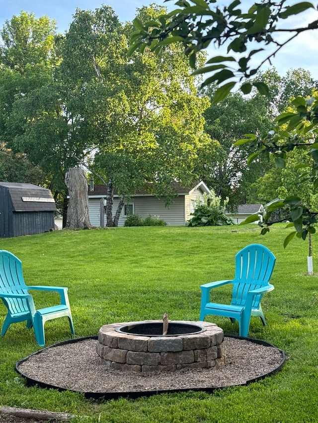 view of yard with an outdoor structure, a fire pit, and a shed