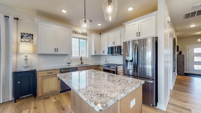 kitchen featuring visible vents, a sink, stainless steel appliances, light wood-type flooring, and backsplash