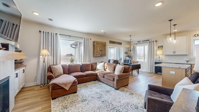 living area with recessed lighting, baseboards, light wood finished floors, and an inviting chandelier