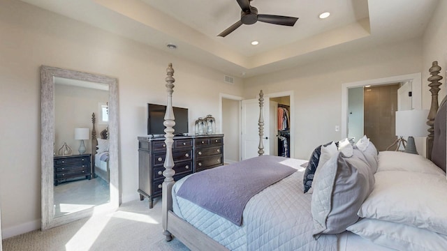 carpeted bedroom with a tray ceiling, a closet, visible vents, a spacious closet, and baseboards