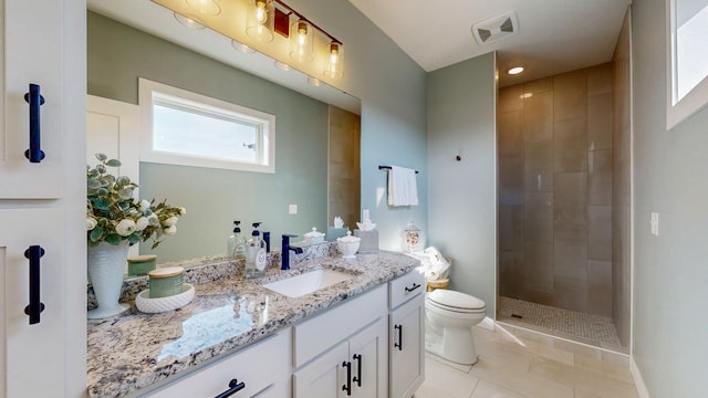 bathroom featuring visible vents, toilet, vanity, tiled shower, and tile patterned floors