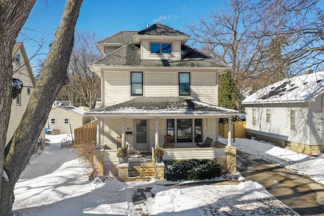 american foursquare style home with covered porch, driveway, roof with shingles, and fence