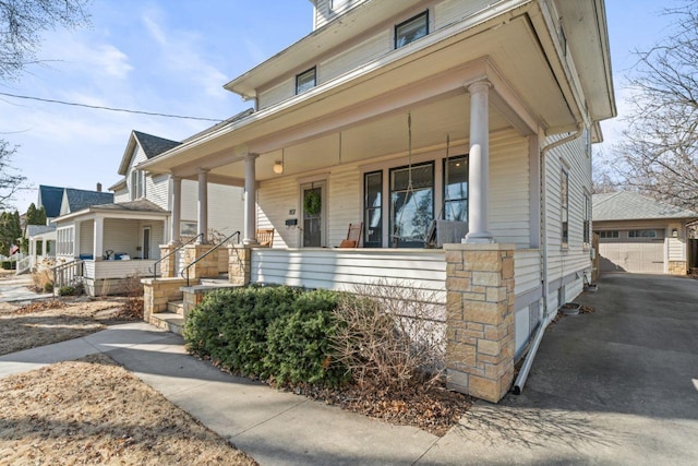 view of front of home with a detached garage, a porch, and an outdoor structure