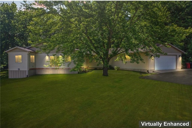 view of yard with a garage and aphalt driveway