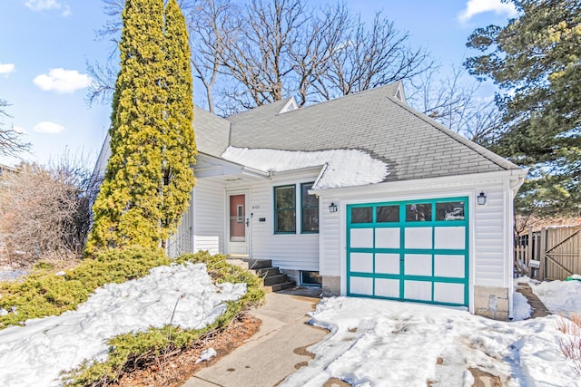 view of front of house featuring a garage, a shingled roof, and fence