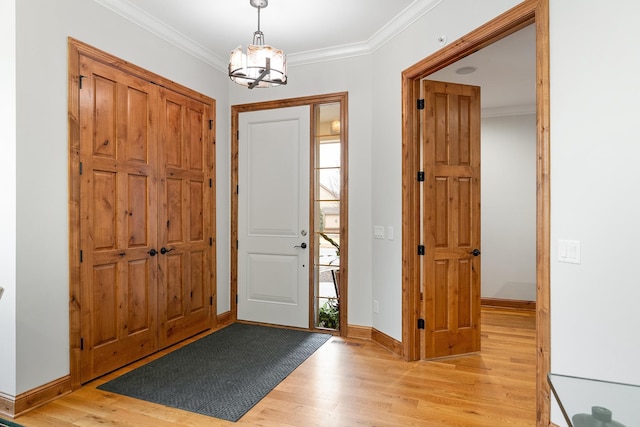 entryway featuring crown molding, light wood-style flooring, baseboards, and an inviting chandelier