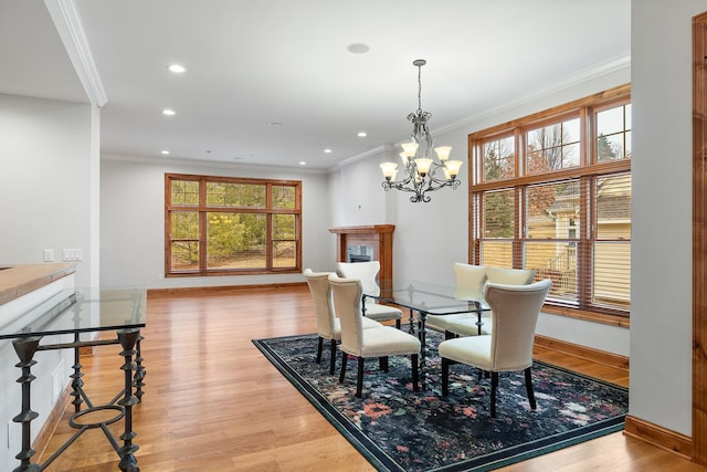 dining space with ornamental molding, light wood finished floors, a fireplace, and baseboards