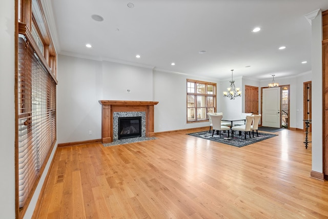 unfurnished living room with light wood finished floors, ornamental molding, and an inviting chandelier