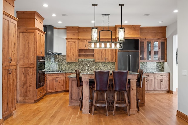 kitchen featuring open shelves, stainless steel appliances, a kitchen island, light wood-type flooring, and wall chimney exhaust hood