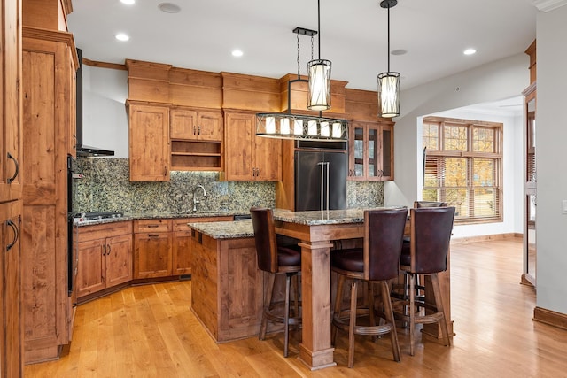 kitchen with decorative backsplash, a breakfast bar area, appliances with stainless steel finishes, brown cabinets, and a center island