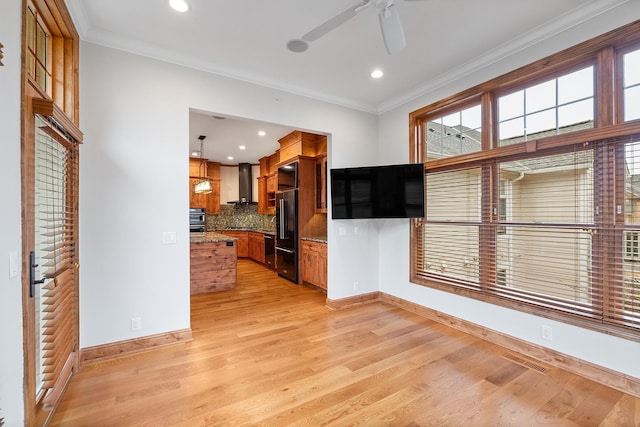 kitchen with visible vents, light wood-style flooring, ornamental molding, freestanding refrigerator, and wall chimney range hood