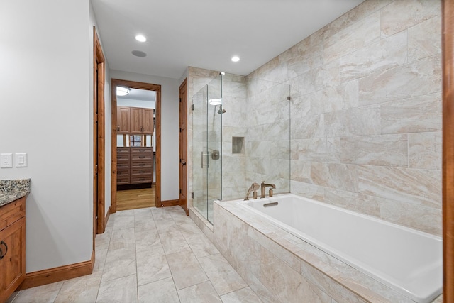 bathroom featuring baseboards, vanity, a shower stall, a bath, and recessed lighting