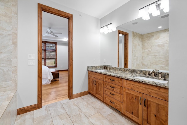 bathroom featuring connected bathroom, a sink, baseboards, and double vanity