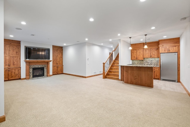 unfurnished living room featuring stairs, a tiled fireplace, light carpet, and recessed lighting