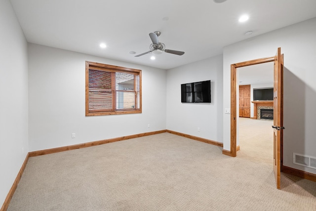 empty room featuring recessed lighting, a fireplace, visible vents, and light colored carpet