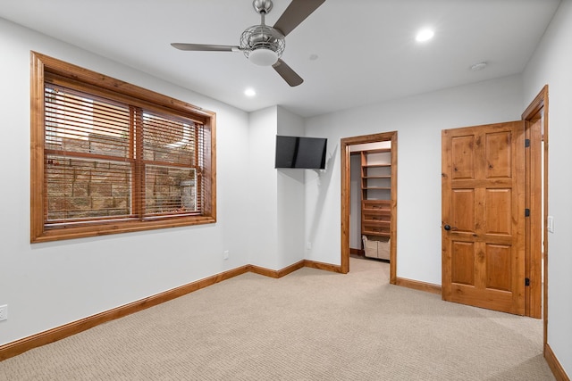 unfurnished bedroom featuring recessed lighting, light carpet, a spacious closet, and baseboards