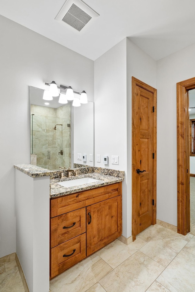 full bath featuring a stall shower, visible vents, vanity, and baseboards