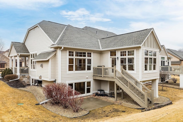 rear view of house featuring roof with shingles, a patio, stairway, and a wooden deck