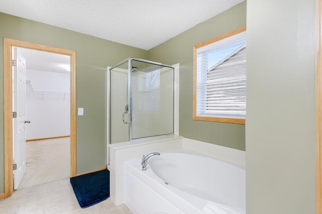 bathroom with a walk in closet, a garden tub, a stall shower, and a textured ceiling