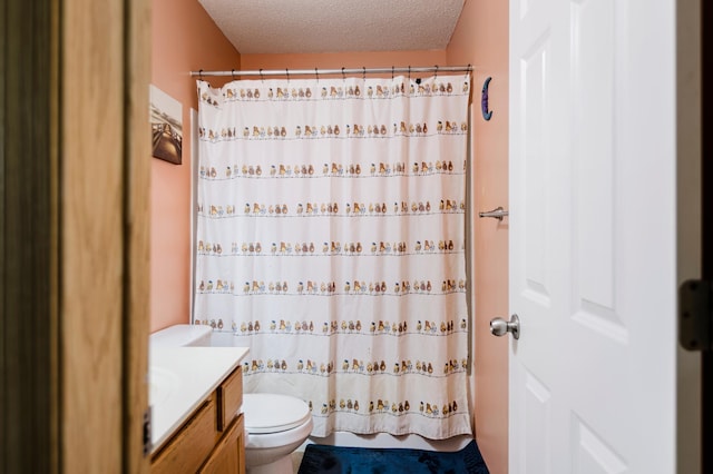 bathroom with a textured ceiling, vanity, and toilet