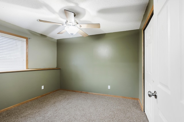 carpeted empty room with a textured ceiling, baseboards, and ceiling fan