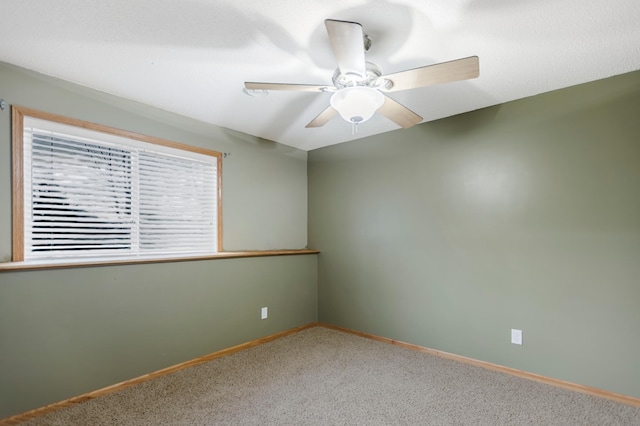 carpeted empty room featuring baseboards and a ceiling fan