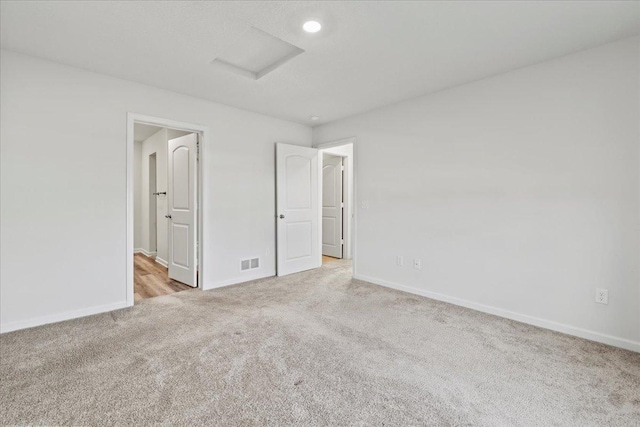 unfurnished bedroom featuring attic access, carpet, visible vents, and baseboards