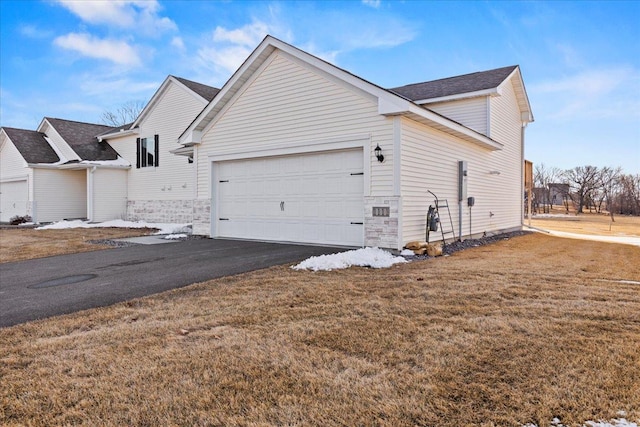 view of property exterior with a yard, aphalt driveway, and an attached garage