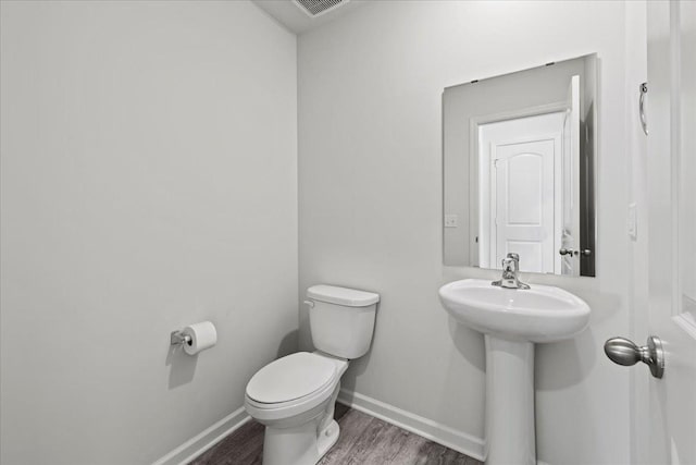 half bathroom with a sink, wood finished floors, toilet, and baseboards