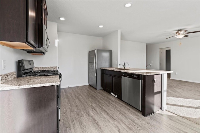 kitchen with appliances with stainless steel finishes, baseboards, a sink, and dark brown cabinets