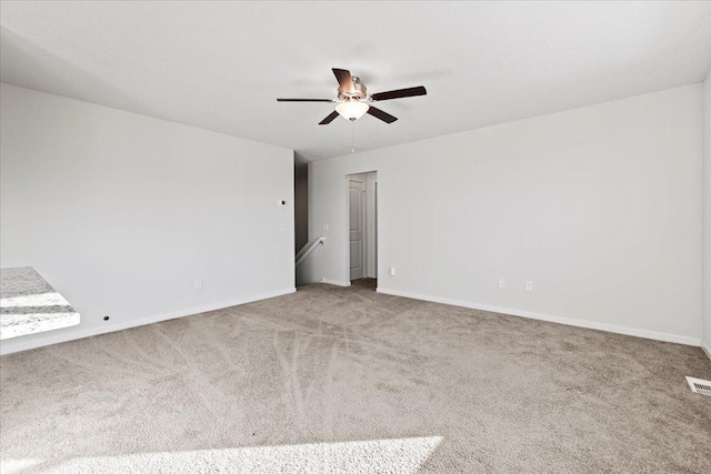 spare room with carpet floors, visible vents, ceiling fan, and baseboards