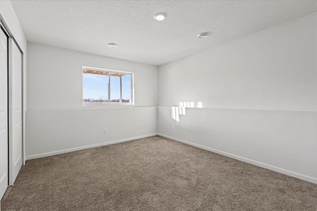 unfurnished bedroom with a textured ceiling, a closet, baseboards, and carpet flooring