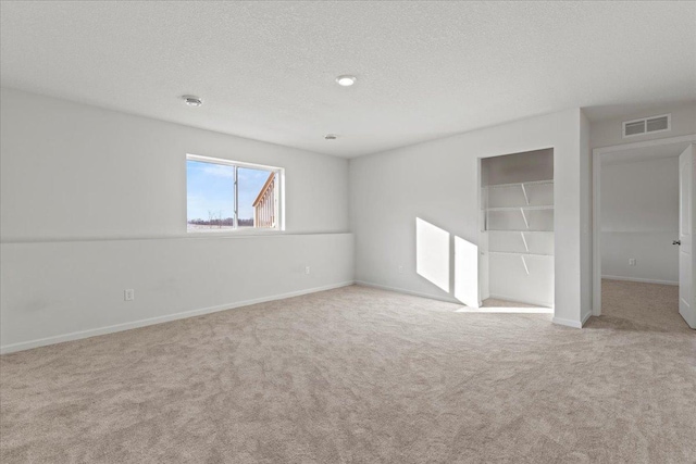 unfurnished bedroom with baseboards, a textured ceiling, visible vents, and carpet flooring