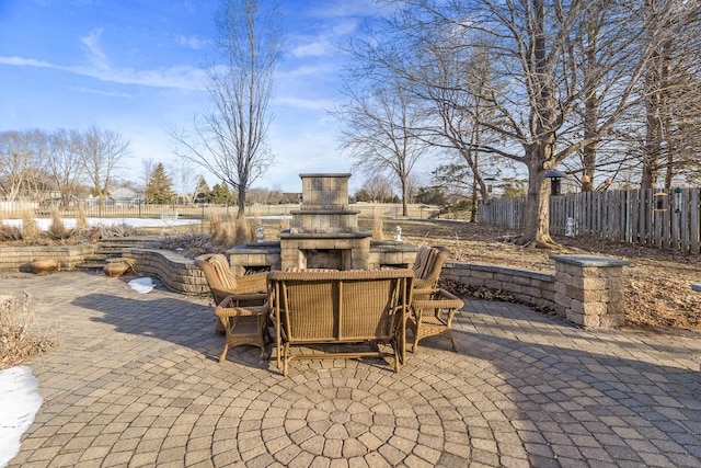 view of patio / terrace featuring fence and an outdoor stone fireplace