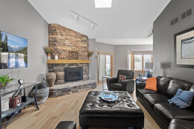 living area with a stone fireplace, wood finished floors, and vaulted ceiling