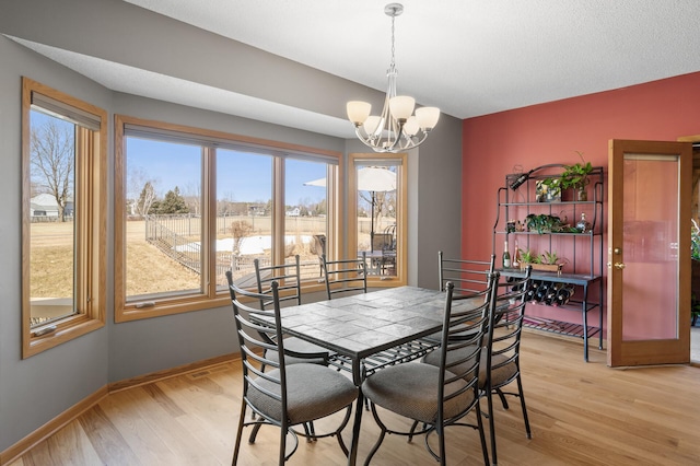 dining room with baseboards, light wood-style floors, and an inviting chandelier