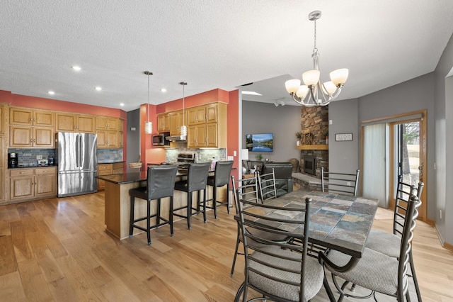 dining space featuring an inviting chandelier, recessed lighting, light wood finished floors, and a textured ceiling