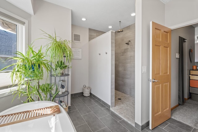 bathroom featuring baseboards, visible vents, a freestanding bath, walk in shower, and tile patterned floors