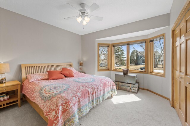 bedroom featuring light colored carpet, a ceiling fan, and baseboards