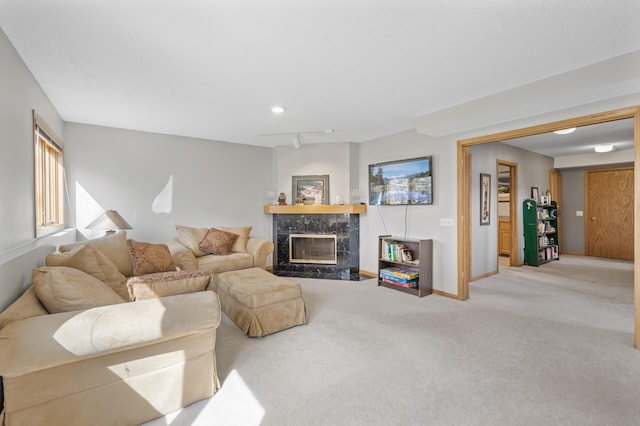 carpeted living area with a premium fireplace, baseboards, and rail lighting