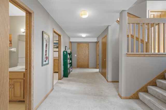 hallway featuring light carpet, stairway, and baseboards