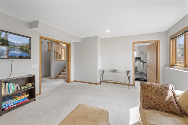 sitting room featuring stairs, light colored carpet, and baseboards